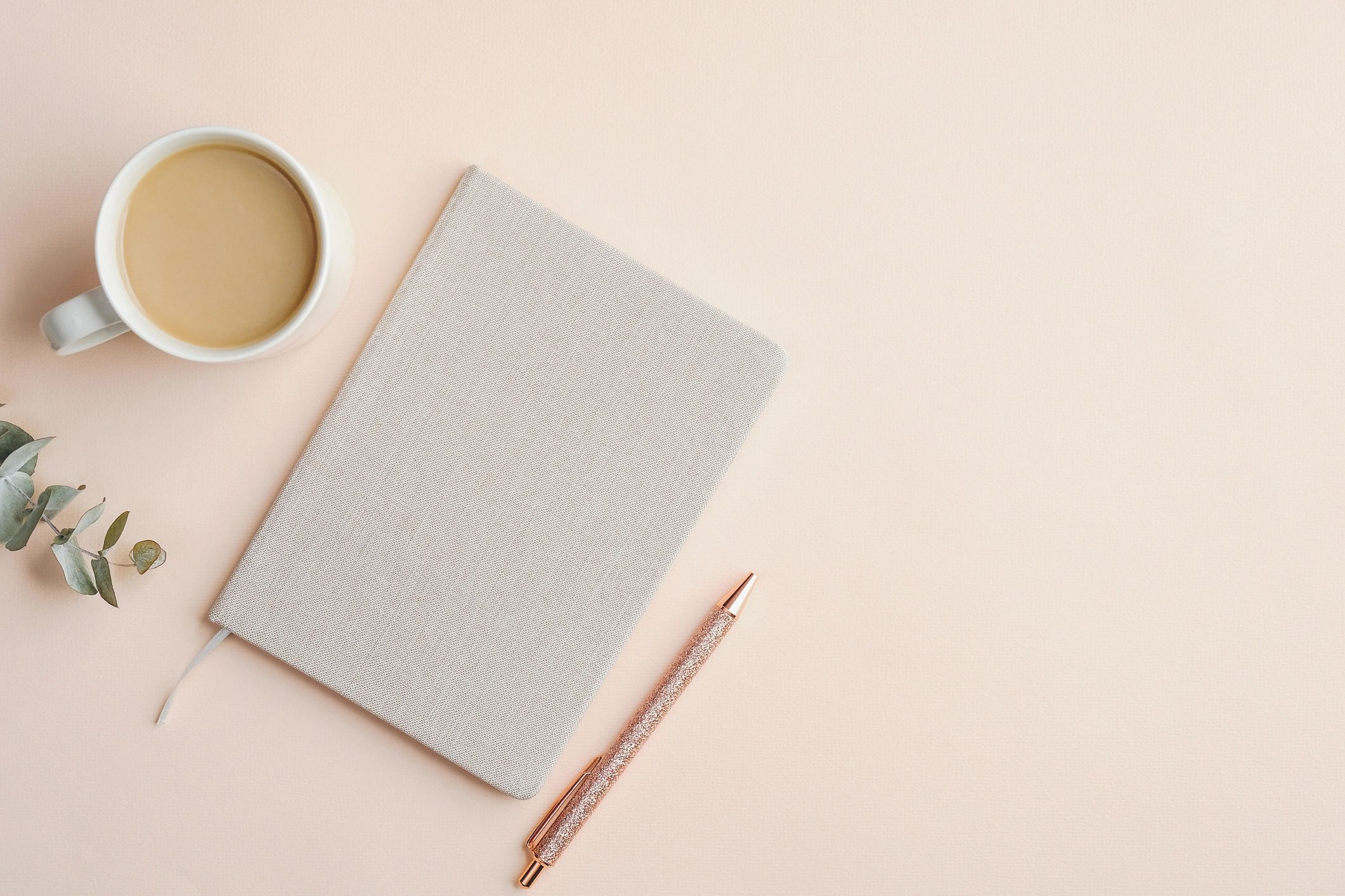 Minimal notebook and coffee on a calm beige workspace